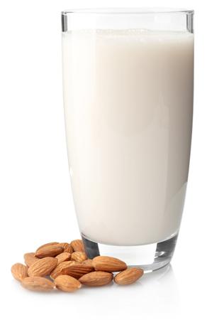 white isolated background, glass of almond milk surrounded by almond nuts