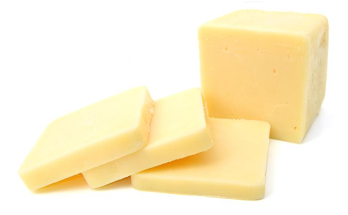 White isolated background, a square block of cheddar cheese with 3 slices cut out and stacked in front of the block