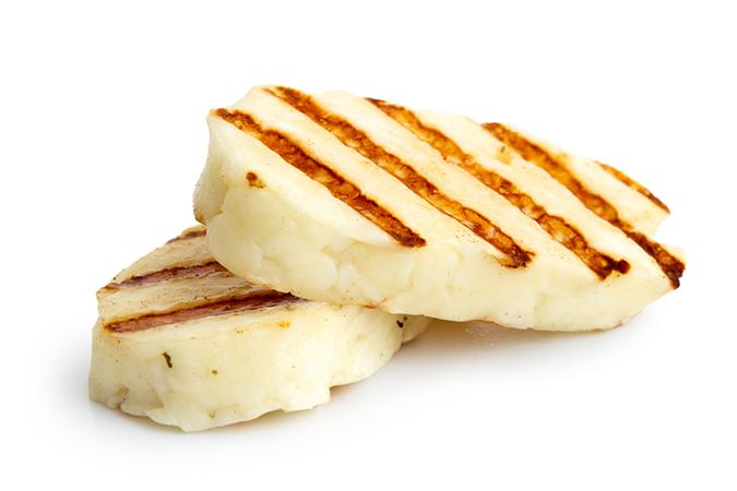 Two pieces of grilled halloumi cheese on each other, on a white isolated background