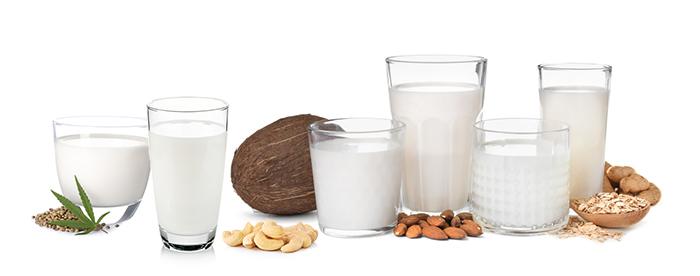 8 different vegan and dairy free milks in glasses, on isolated white background