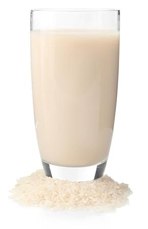 Glass of rice milk, glass surrounded by a pile of rice, on a white isolated background