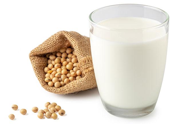 silhouette white background glass of soya milk, with soybeans laying at the base of the glass